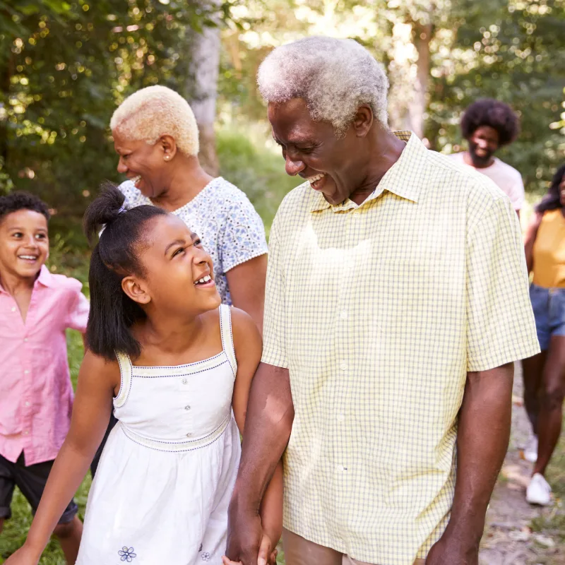 A multigenerational family walking together outdoors, grandparents, parents, and children sharing time in the sun