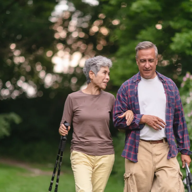 A couple walking outdoors together with hiking poles, active and enjoying retirement