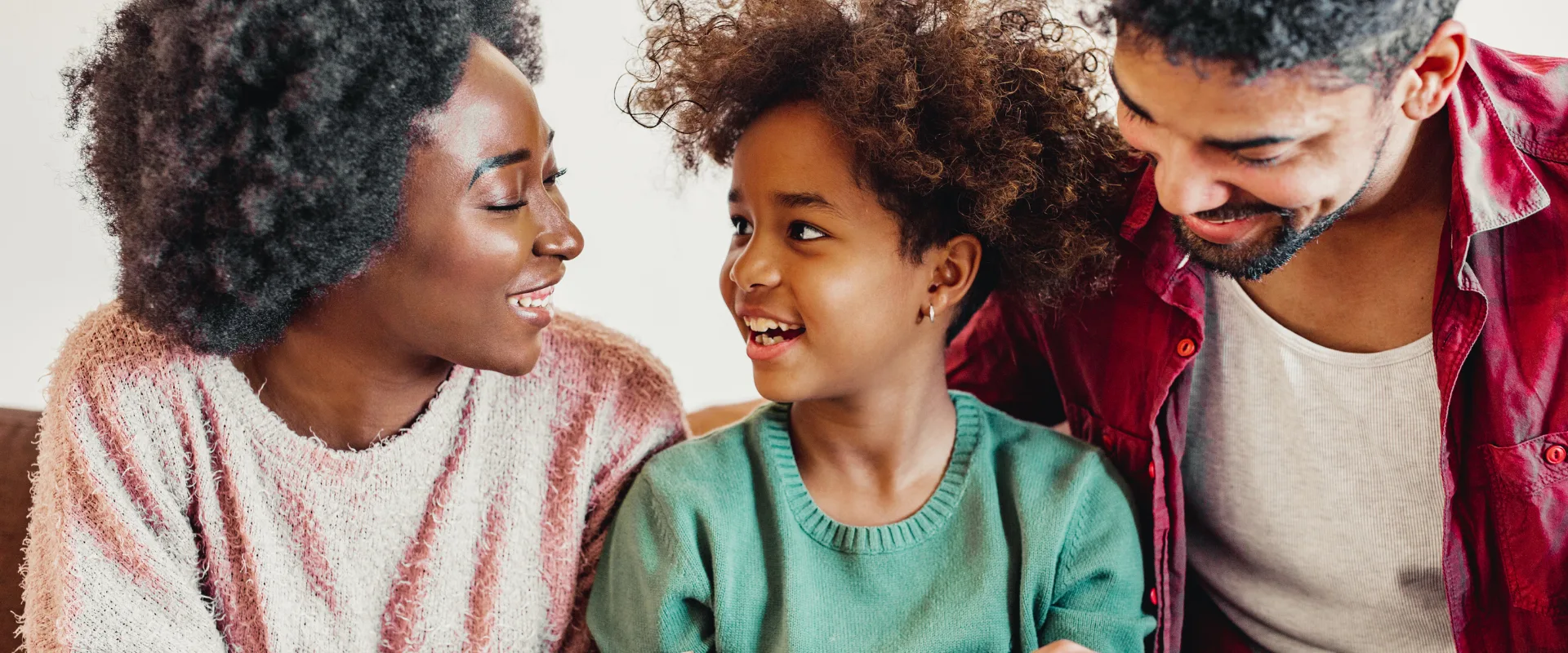 A family — mother, daughter, and father — smiling warmly together, representing the loved ones that IUL protects