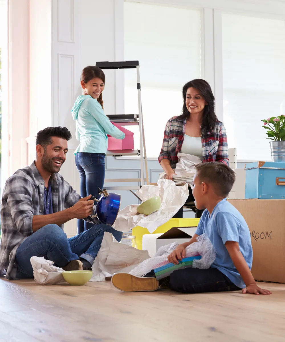 A family happily unpacking moving boxes in their bright new home