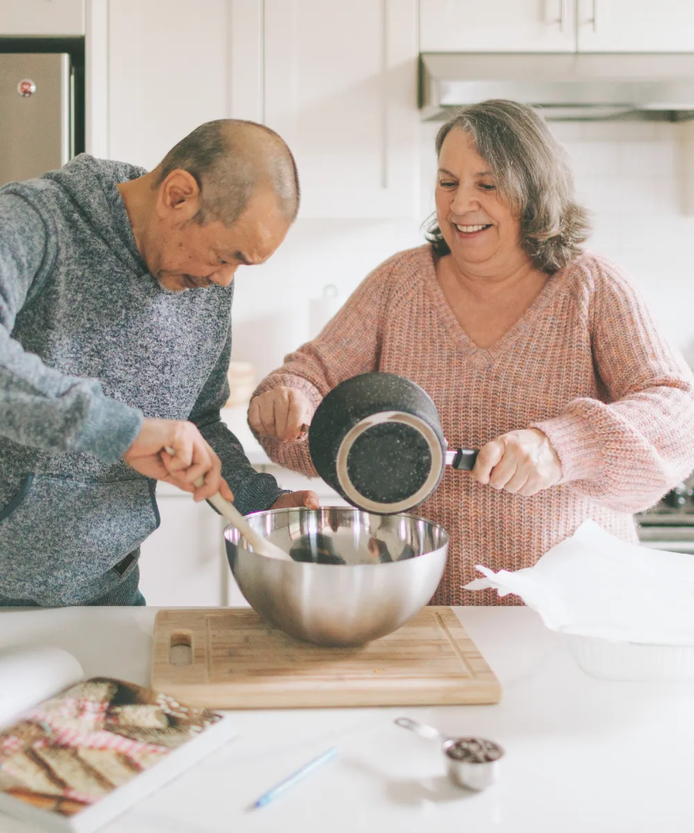 An older couple cooking together in a bright kitchen, representing the active retirement that IUL income can help sustain