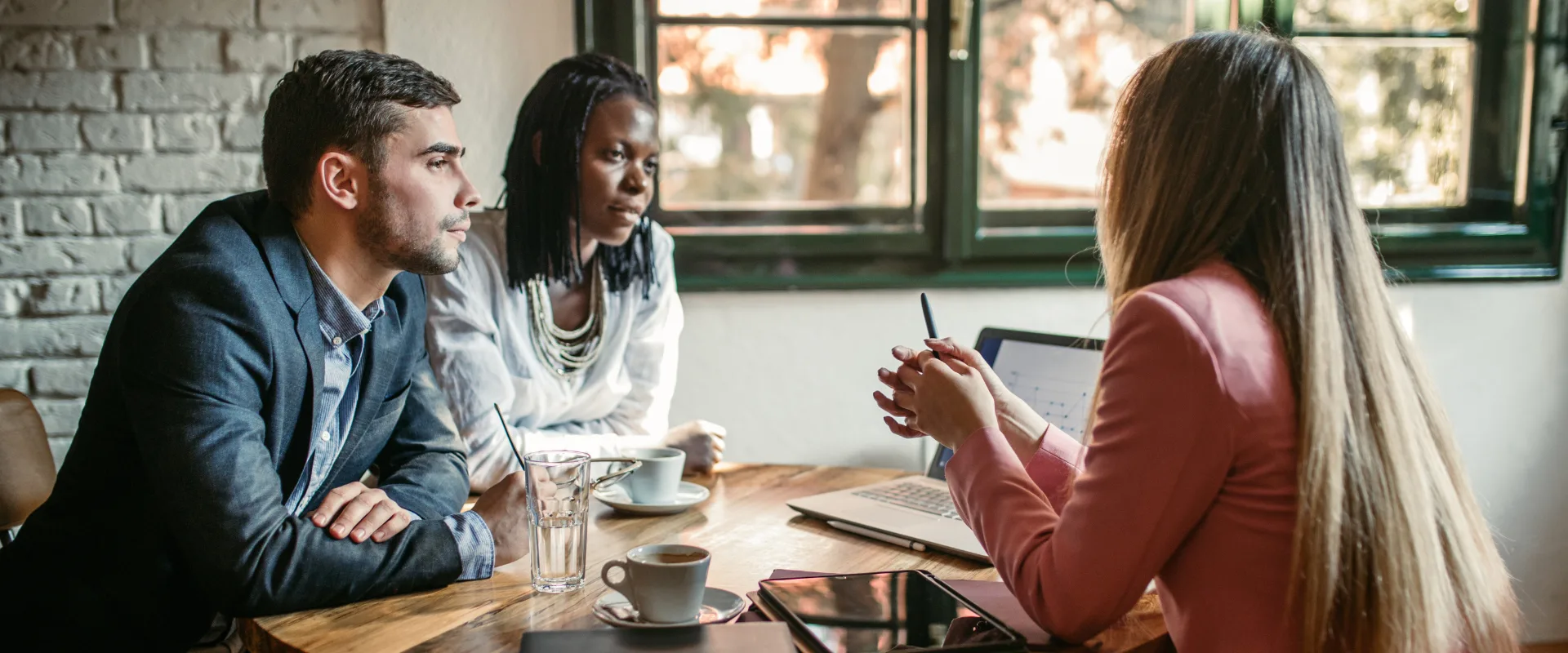 An FCPC agent leaning forward in focused conversation with a couple seated across from them, representing the personalized, no-pressure guidance available through a free review
