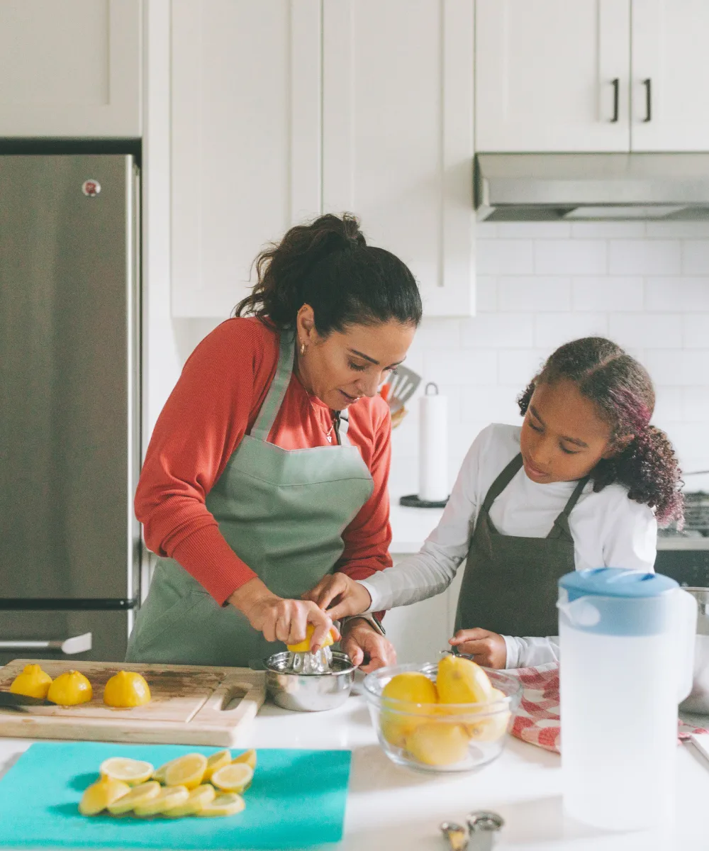 A mother and daughter cooking together in a bright kitchen, representing the everyday life that supplemental health coverage helps protect