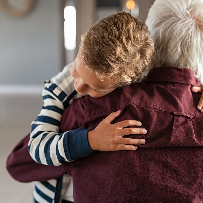 A grandfather embracing his grandson, representing the dignity and peace of mind that terminal illness coverage provides